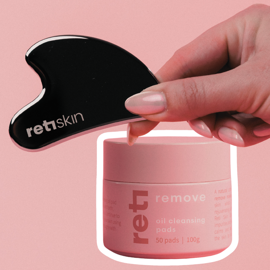 Hand holding a black skincare tool with a pink container labeled &
